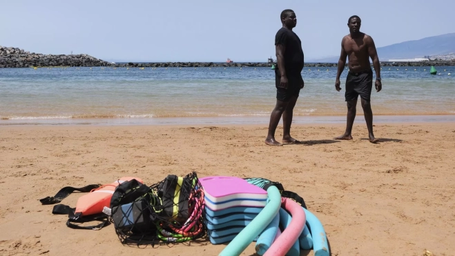 Dos de los migrantes que asisten al curso de natación impartido por la ONG Proemaid, enfocado a ayudar a los supervivientes de la Ruta Canaria a volver a vincularse con el mar después de su travesía, en la playa de las Teresitas en Santa Cruz de Tenerife. / ALBERTO VALDÉS-EFE