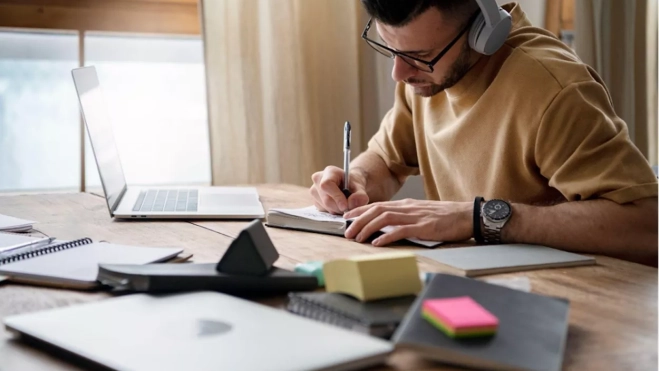 Estudiante escribe con unos cascos puestos