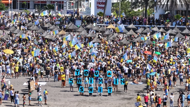 Manifestantes se congregan en la playa de Troya entre turistas con el mensaje "you swin in shit (te estás bañando en mierda)" / Iván Pérez Rubiralta