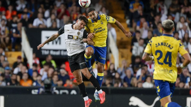 El delantero del Valencia, Hugo Duro (i), disputa el balón ante el defensa de la UD Las Palmas, Alex Suárez. / MANUEL BRUQUE-EFE