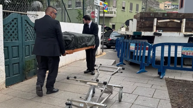 Dos trabajadores de Mémora trasladan un ataúd al coche fúnebre / AH