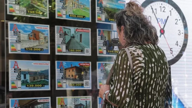 Una mujer mira el escaparate de una inmobiliaria con precios de viviendas / EFE Una mujer mira el escaparate de una inmobiliaria con precios de viviendas / EFE